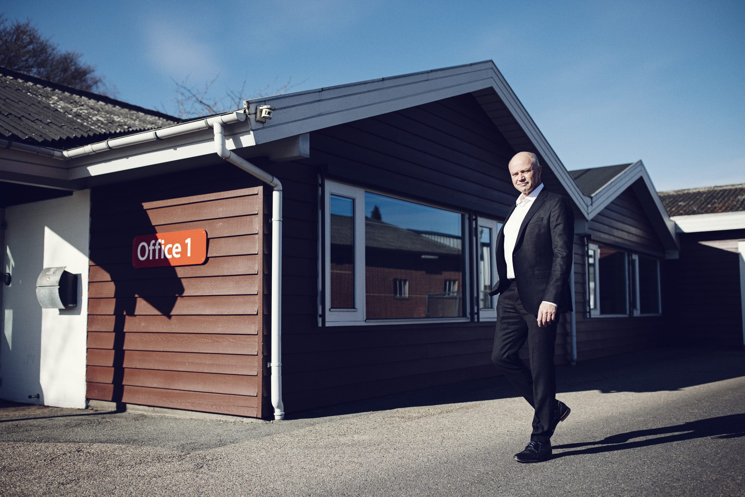 Gående mand med lille kontorbygning i baggrunden